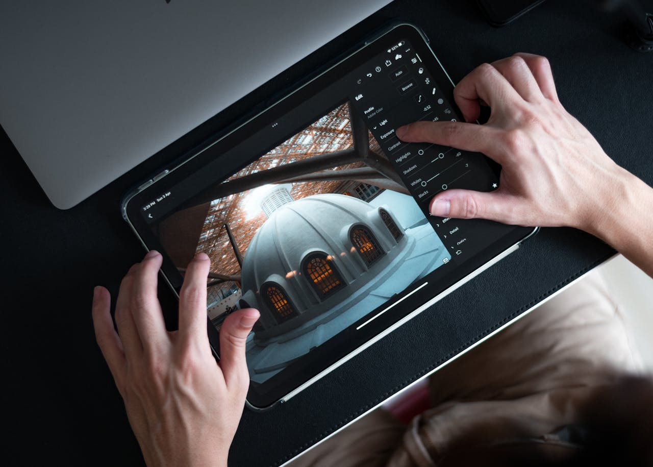 Hands editing architectural photo on tablet using Lightroom app.
